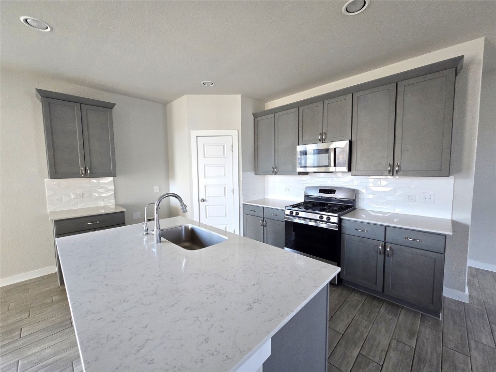 141 Appleberry Lane Elgin, TX 78621 - Photo 2 of 17 a kitchen with kitchen island granite countertop a stove top oven sink and cabinets