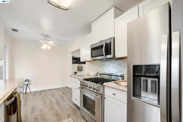 a kitchen with stainless steel appliances granite countertop a refrigerator a stove top oven a sink and dishwasher