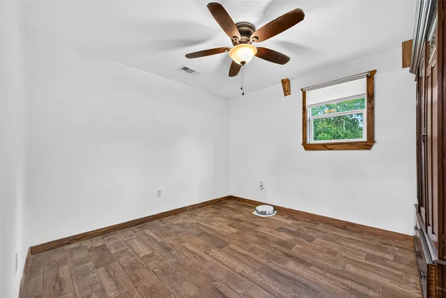 an empty room with a window and a ceiling fan