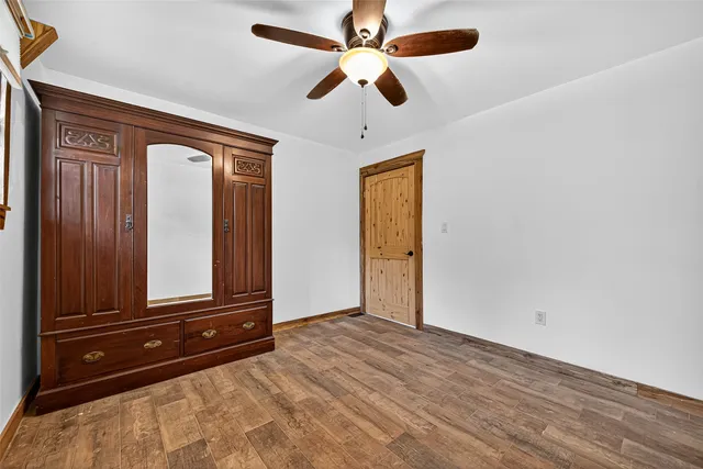 an empty room with wooden floor closet and fan