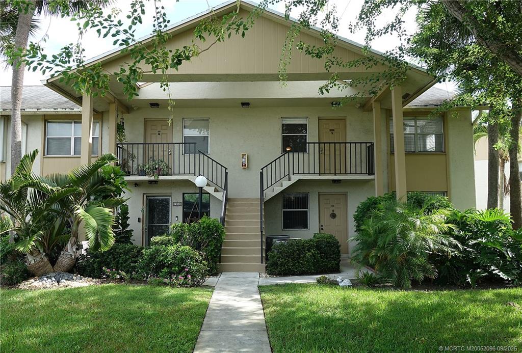 3101 Southeast Aster Lane, Unit 1908 Stuart, FL 34994 - Photo 1 of 24 a view of a white house next to a yard with plants and trees