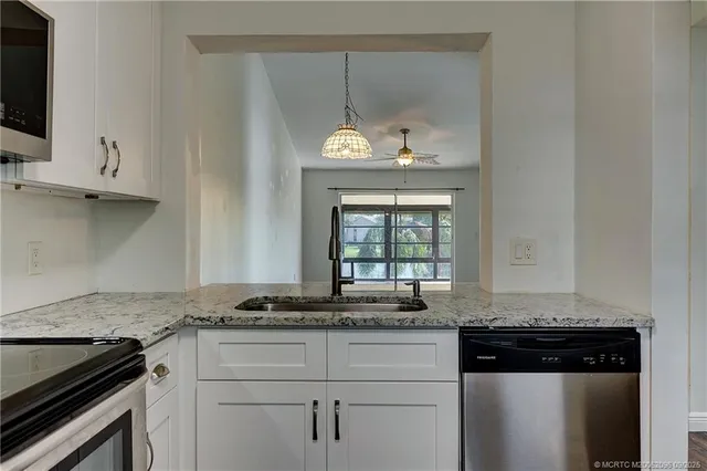 a kitchen with granite countertop a stove and a white cabinets