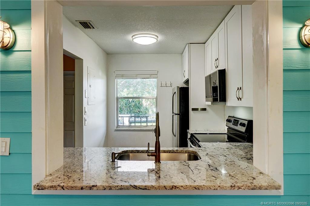 3101 Southeast Aster Lane, Unit 1908 Stuart, FL 34994 - Photo 5 of 24 a kitchen with sink a window and a view of living room
