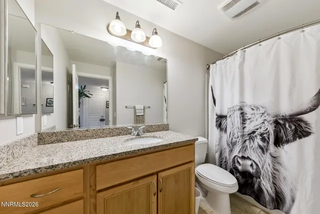a bathroom with a granite countertop sink mirror vanity and toilet