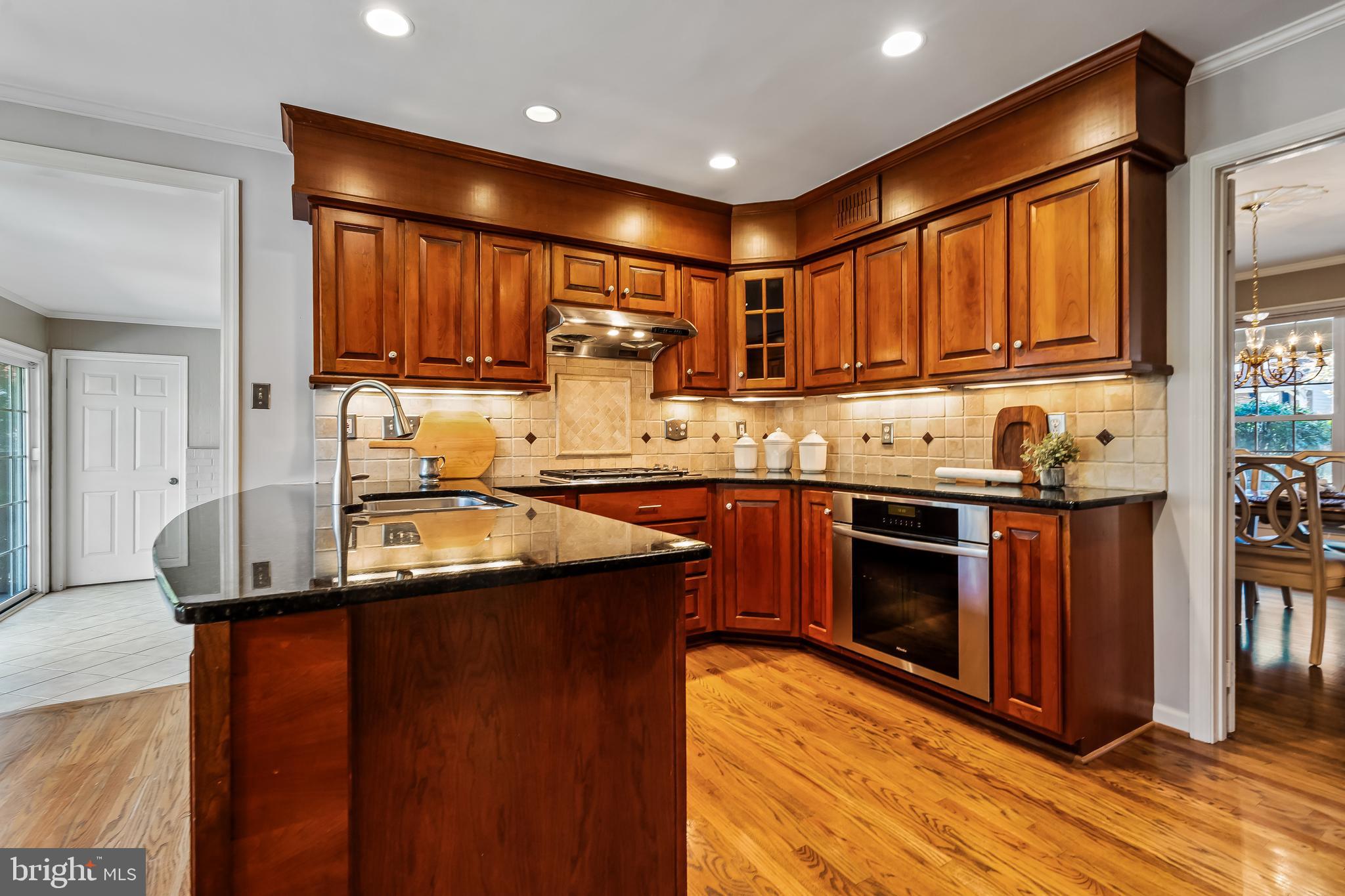 2716 Glencroft Road Vienna, VA 22181 - Photo 20 of 66 a kitchen with kitchen island granite countertop wooden cabinets a sink and a stove
