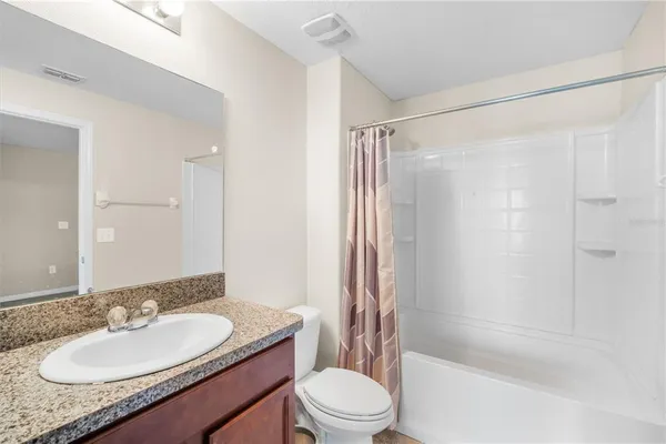 a bathroom with a granite countertop sink toilet a mirror a bathtub and shower