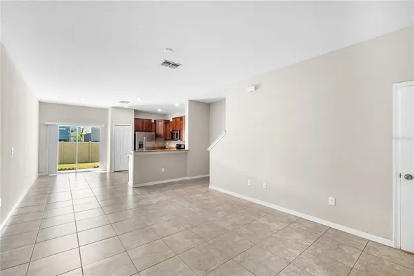 a view of empty room with kitchen and window