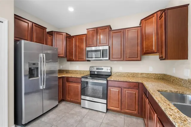 a kitchen with kitchen island granite countertop wooden cabinets stainless steel appliances and a counter space