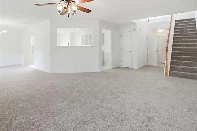 an empty room with chandelier fan and windows