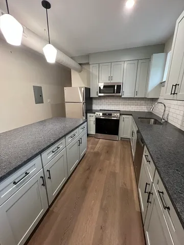 a large kitchen with stainless steel appliances granite countertop a sink a stove and a wooden floors