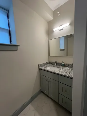 a bathroom with a granite countertop sink and a mirror