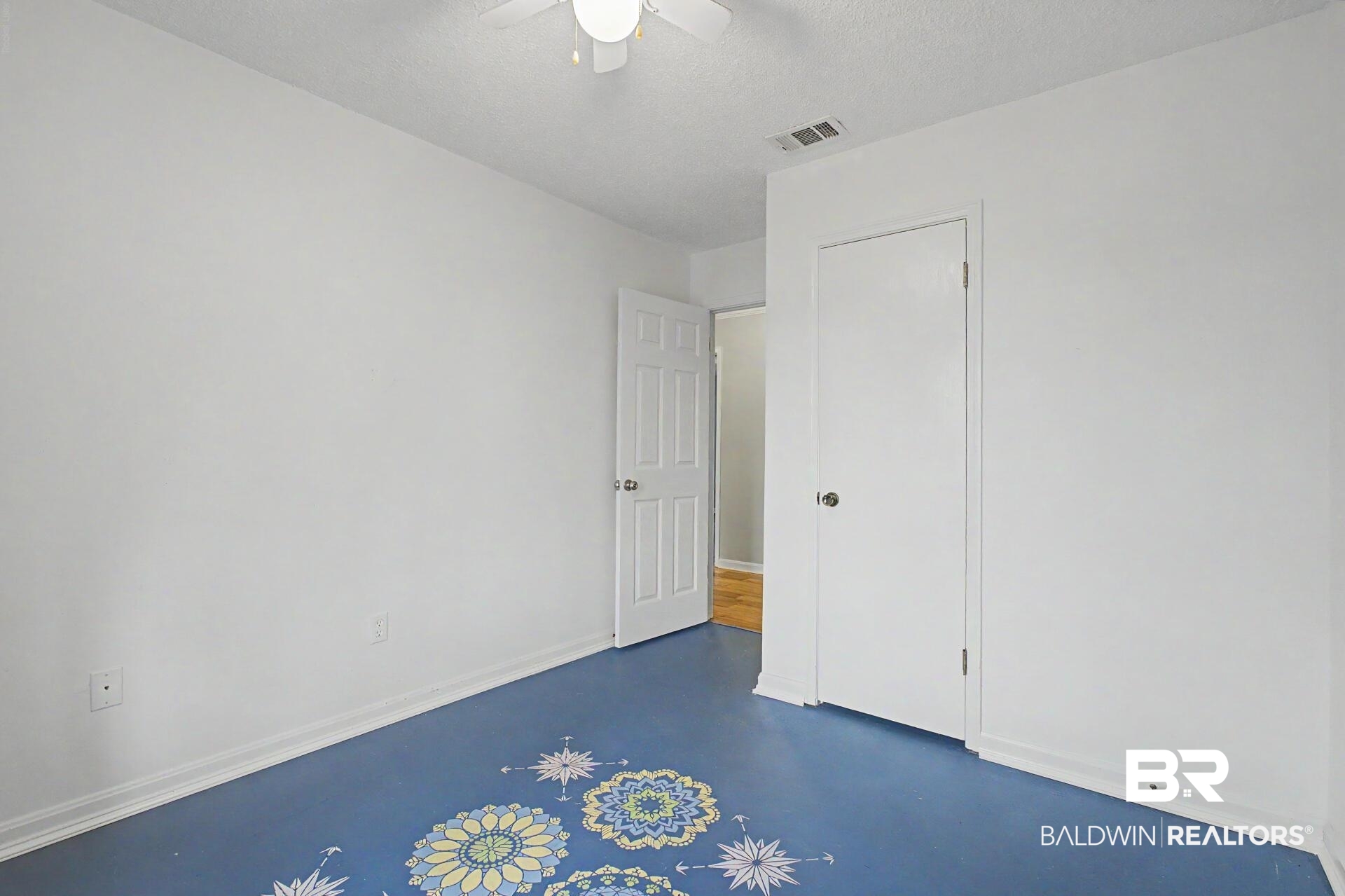 3791 Robinsonville Road Atmore, AL 36502 - Photo 37 of 47 Bright room featuring a blue floor with decorative patterns, white walls, and a ceiling fan