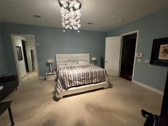 a bedroom with a large bed and a chandelier