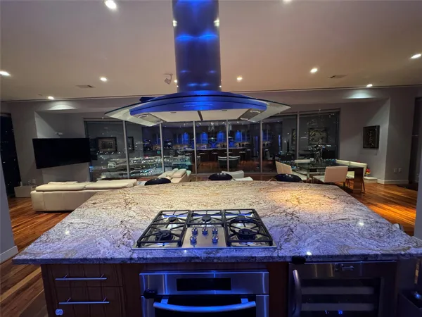 a kitchen with stainless steel appliances granite countertop a stove and a view of living room
