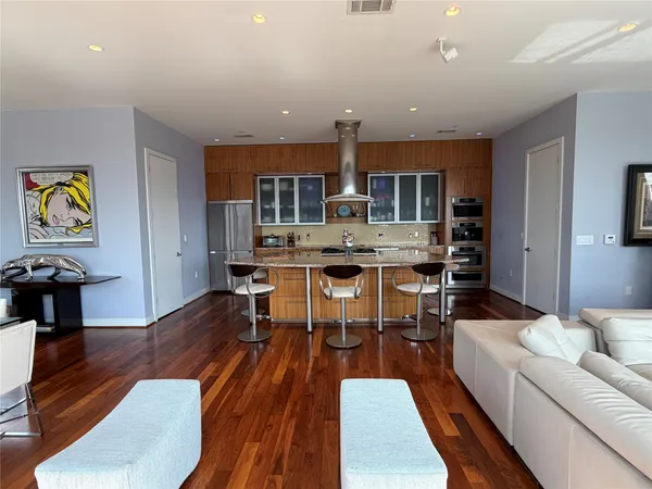 a living room with stainless steel appliances furniture and a kitchen view