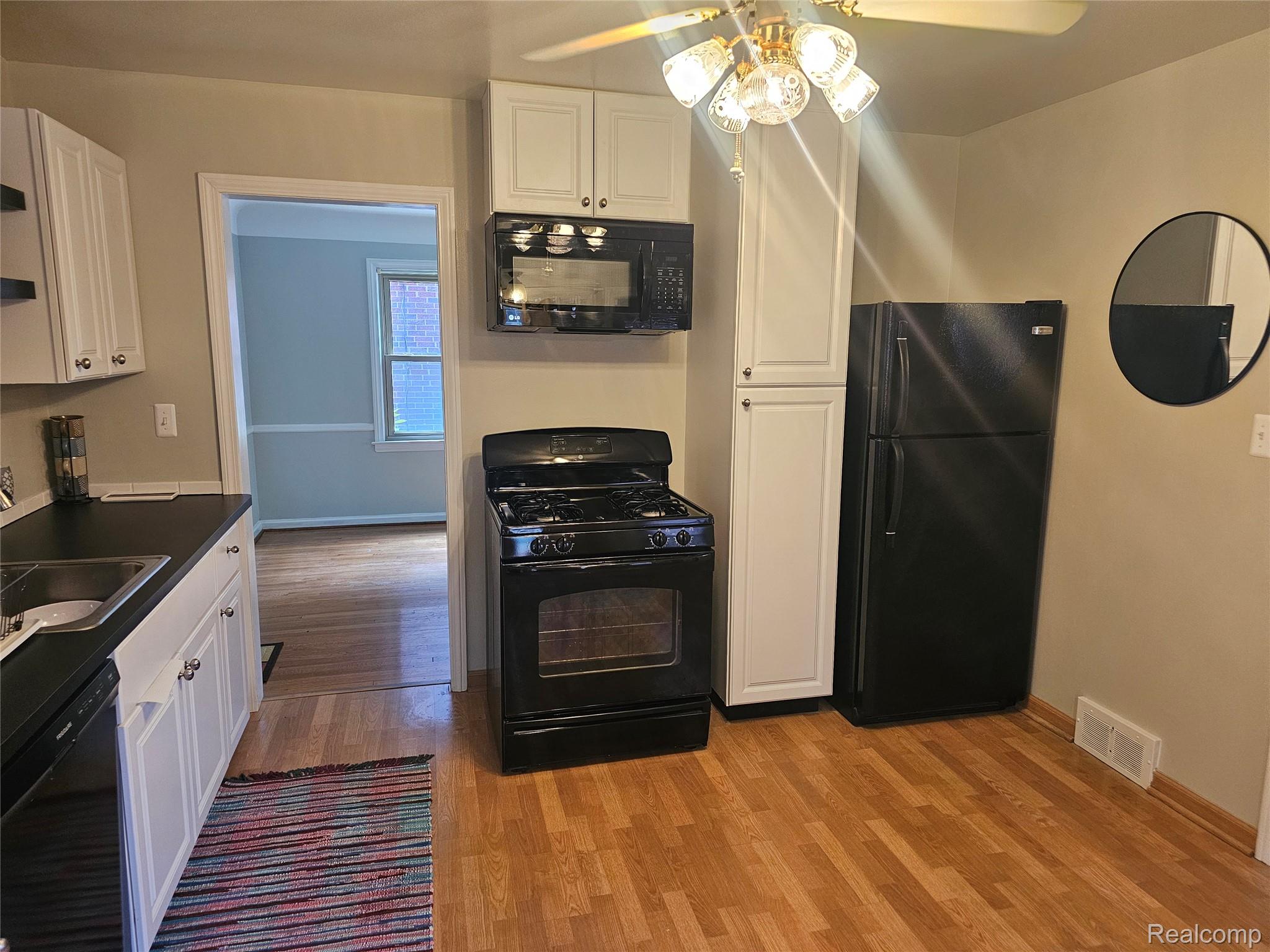 5240 Harvard Road Detroit, MI 48224 - Photo 10 of 18 Kitchen featuring wood-finish flooring, white cabinetry, black appliances including a gas range and refrigerator, and a ceiling fan with integrated lighting