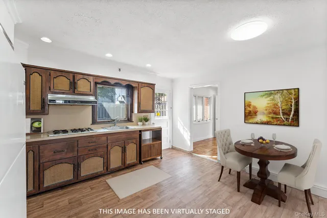 a view of kitchen island a sink wooden floor and chairs