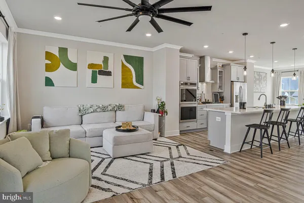 a living room with stainless steel appliances kitchen island granite countertop furniture and a wooden floor