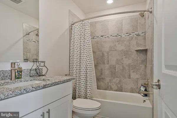 a bathroom with a granite countertop sink toilet and shower