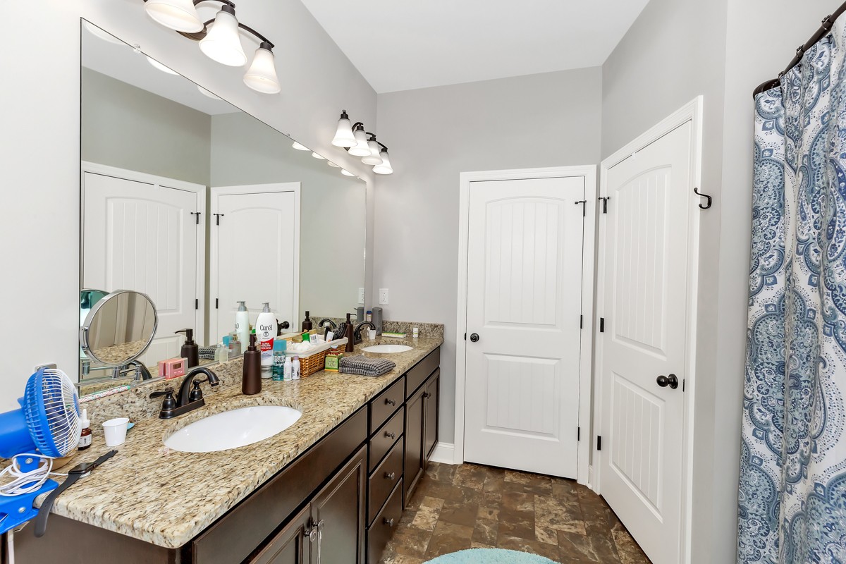 247 Mabel Hill Road Toney, AL 35773 - Photo 16 of 29 a bathroom with double vanity sinks a toilet a mirror and shower