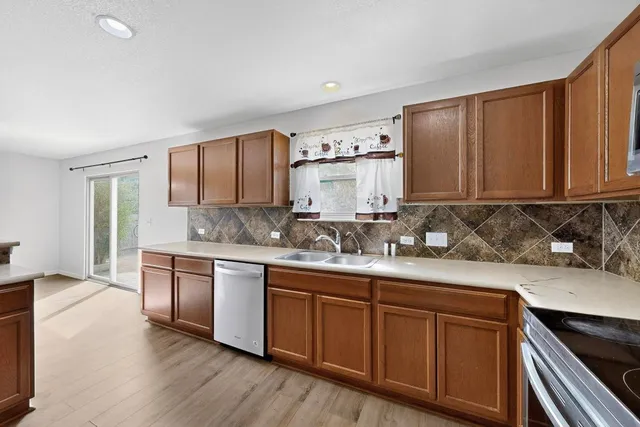 a kitchen with stainless steel appliances granite countertop wooden cabinets a sink and dishwasher a stove with wooden floors