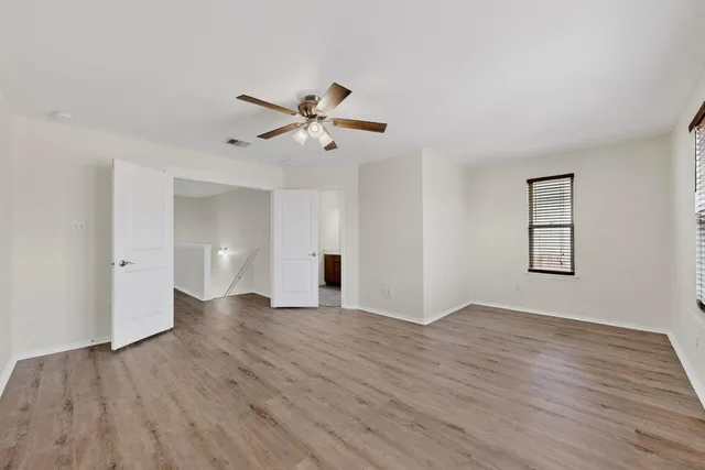 an empty room with wooden floor and ceiling fan