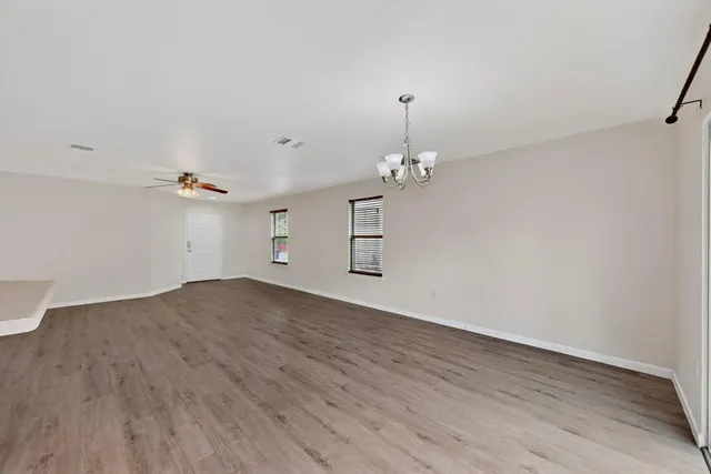 an empty room with wooden floor and ceiling fan