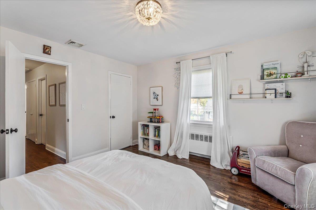 53 Stuart Place Manhasset, NY 11030 - Photo 23 of 32 a bedroom with a bed and a chandelier