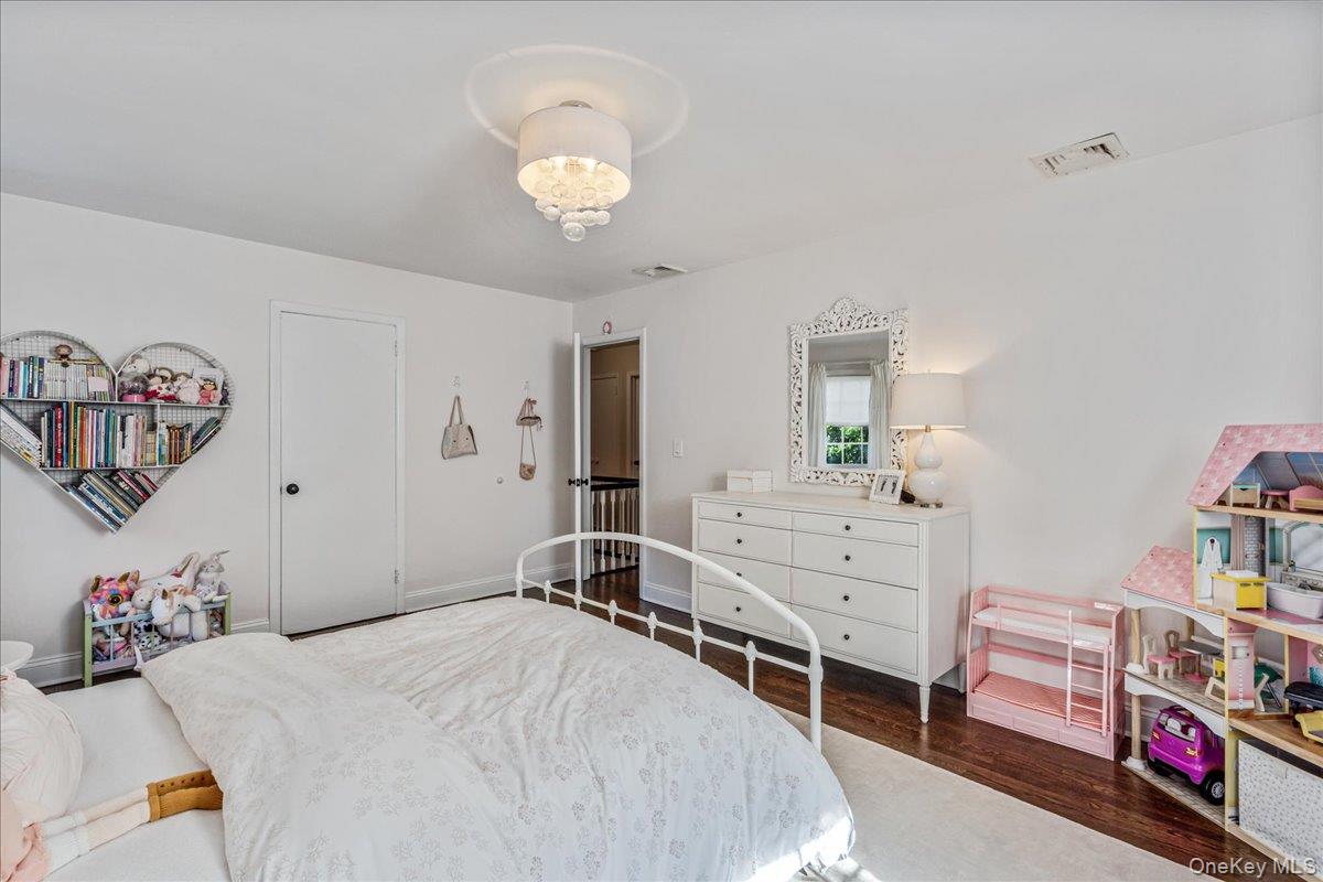 53 Stuart Place Manhasset, NY 11030 - Photo 25 of 32 a bedroom with a bed and a chandelier