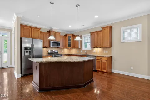 a large kitchen with stainless steel appliances granite countertop a sink a stove a refrigerator a center island and cabinets