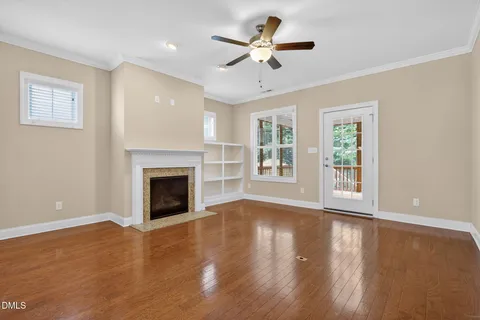 a view of an empty room with wooden floor fireplace and a window