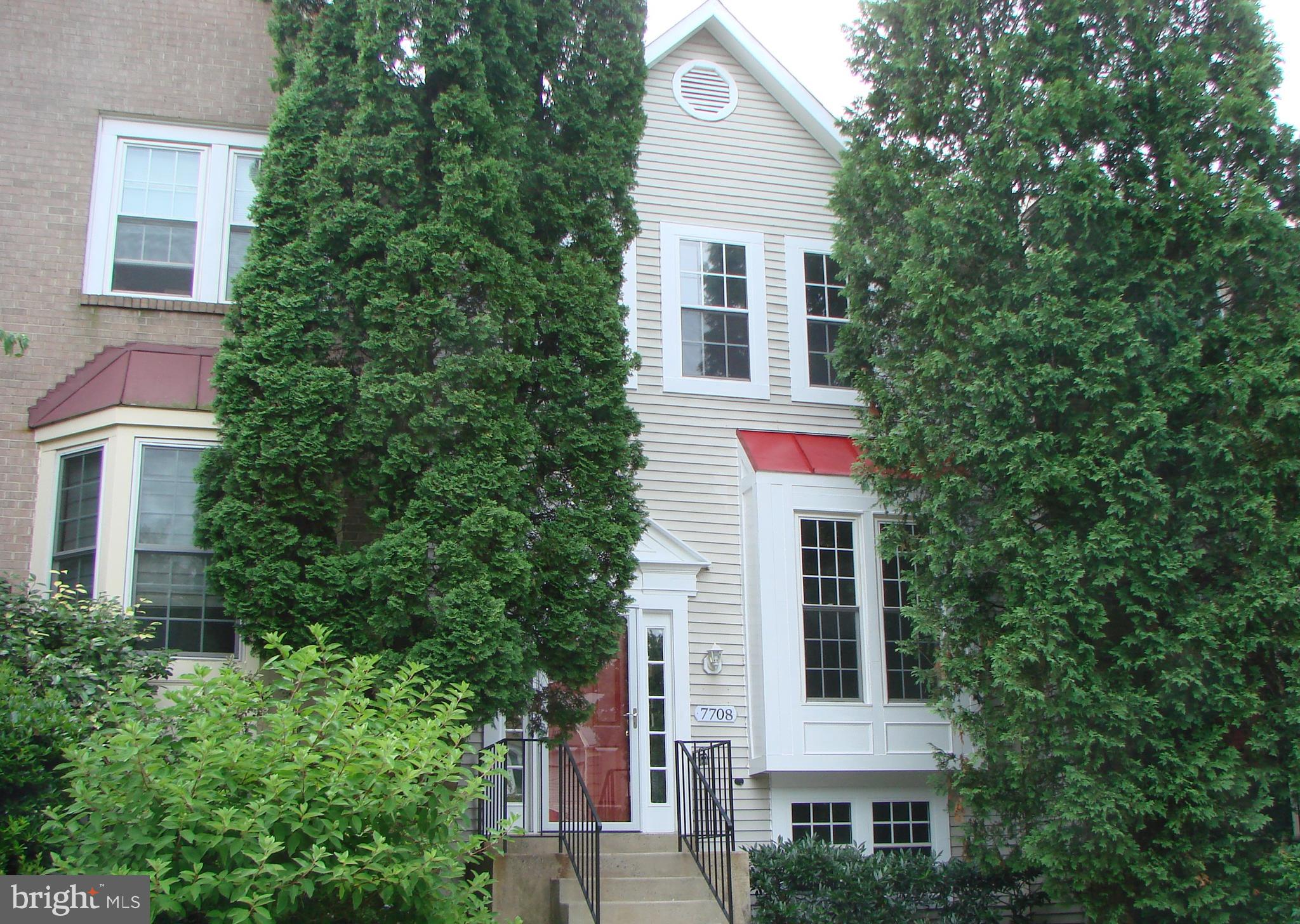 a front view of a house with plants and trees