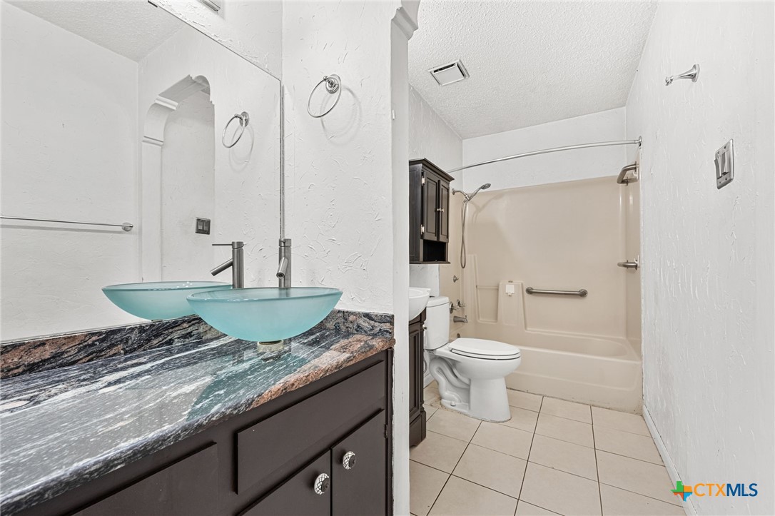 1015 Old Mill Road, Unit 4D Salado, TX 76571 - Photo 13 of 22 a bathroom with a granite countertop sink a toilet and a shower