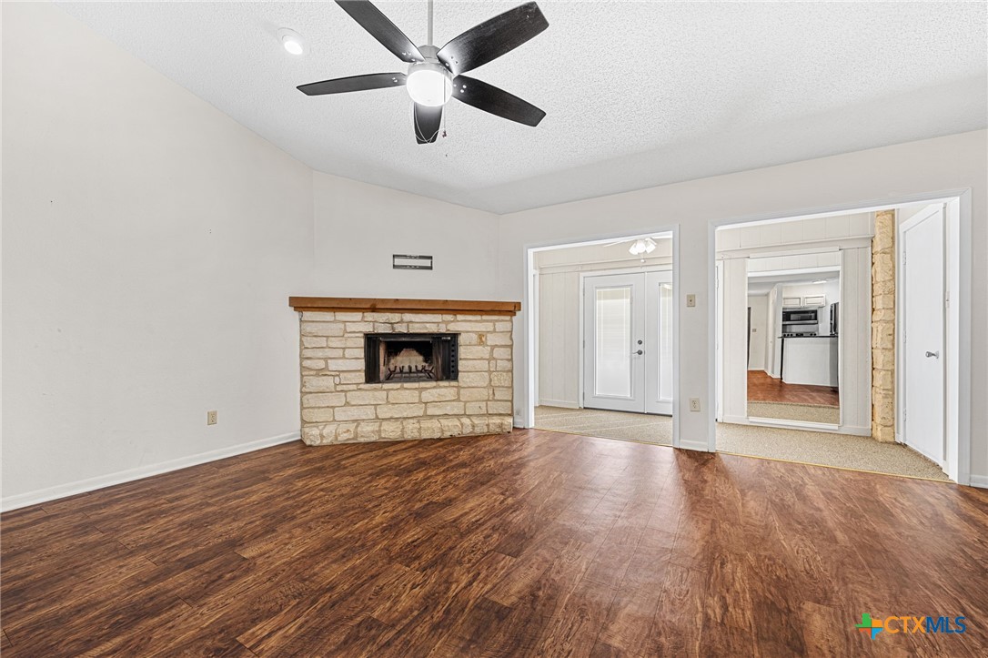 1015 Old Mill Road, Unit 4D Salado, TX 76571 - Photo 5 of 22 an empty room with wooden floor a ceiling fan a fireplace and windows