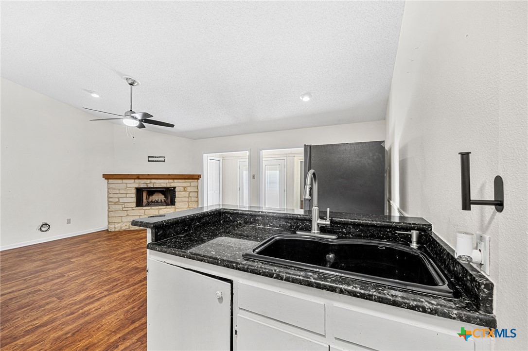 1015 Old Mill Road, Unit 4D Salado, TX 76571 - Photo 7 of 22 a kitchen with granite countertop a sink and a stove top oven with wooden floor