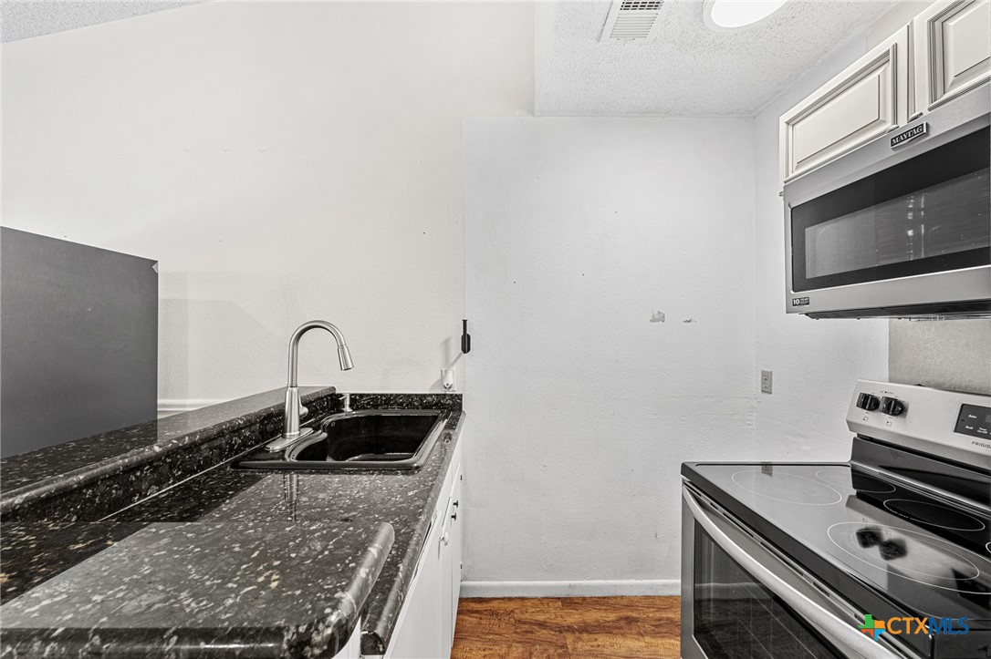 1015 Old Mill Road, Unit 4D Salado, TX 76571 - Photo 8 of 22 a kitchen with granite countertop a stove and a sink