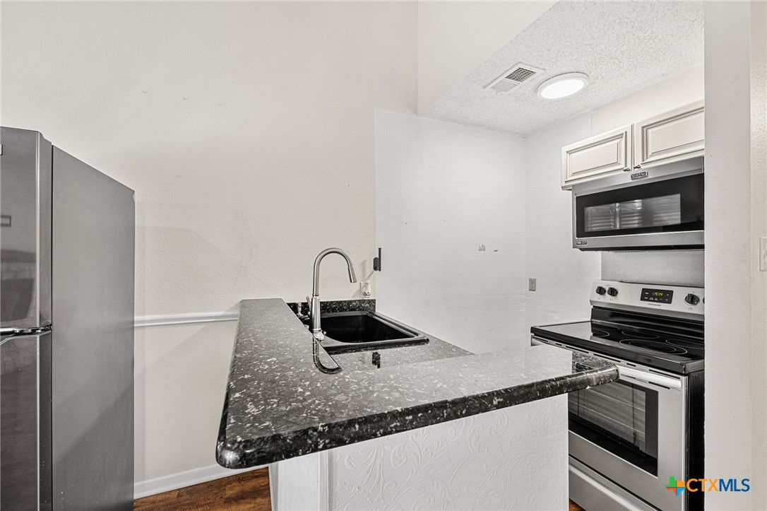 1015 Old Mill Road, Unit 4D Salado, TX 76571 - Photo 9 of 22 a kitchen with stainless steel appliances granite countertop a sink stove and refrigerator