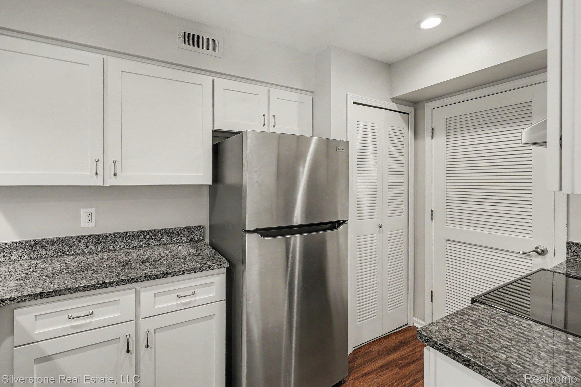 1502 Meadowside Drive Rochester, MI 48307 - Photo 13 of 27 Kitchen featuring stainless steel refrigerator, white cabinetry, speckled countertops, and wood-finish flooring