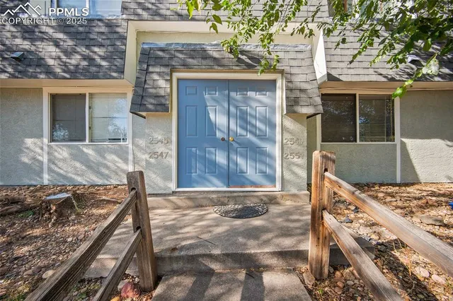 a view of a house with a barbeque grill and wooden fence