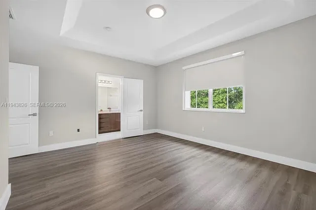 a view of an empty room with wooden floor and closet