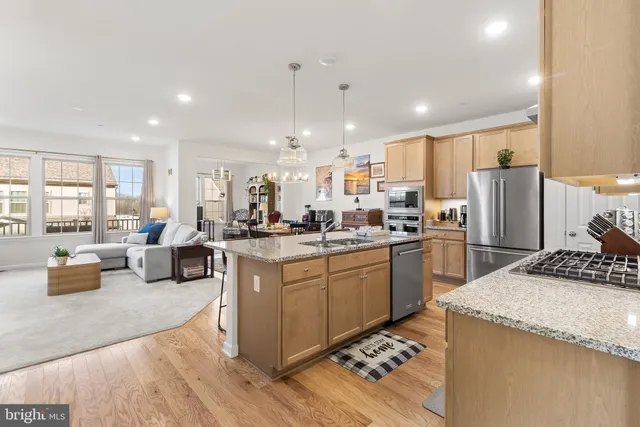 a kitchen with stainless steel appliances kitchen island granite countertop a sink stove and refrigerator