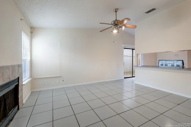 a view of an empty room and chandelier fan