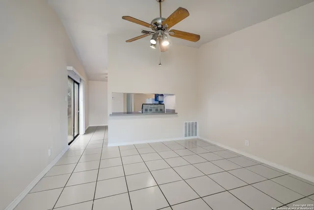 a view of an empty room and chandelier fan