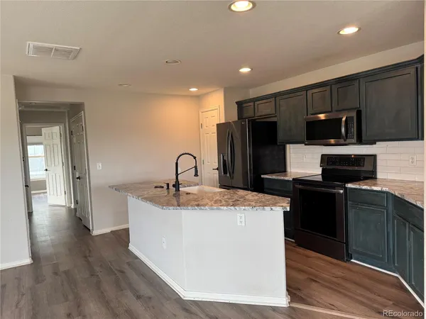 a kitchen with kitchen island stainless steel appliances a sink and a refrigerator