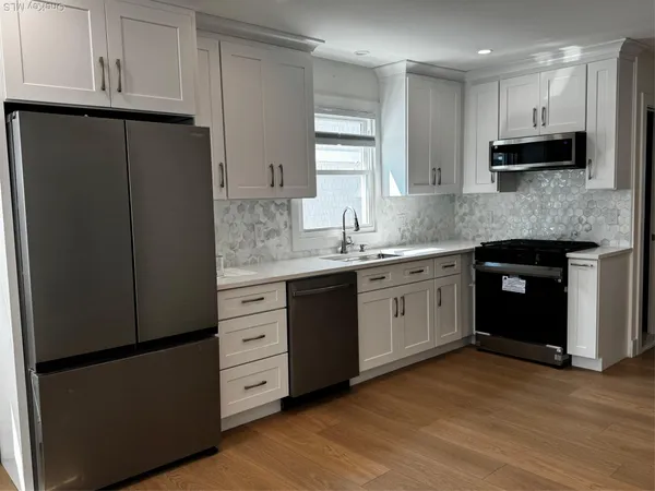 a kitchen with stainless steel appliances granite countertop a refrigerator a sink a stove and oven with wooden floor