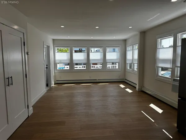 a view of an empty room with window and wooden floor