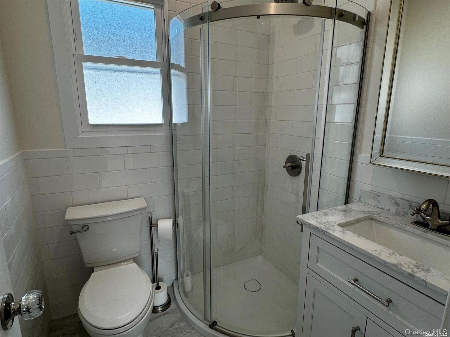 253 West Market Street, Unit UPPR Long Beach, NY 11561 - Photo 8 of 12 a bathroom with a shower a toilet and sink