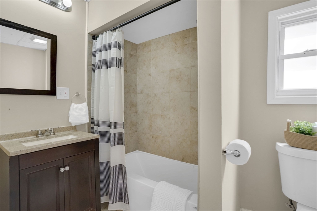 38 Whitman Street Chicopee, MA 01013 - Photo 13 of 29 a bathroom with a sink a toilet a mirror a vanity and shower