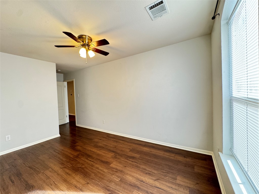 3404 Bratton Ridge Crossing Austin, TX 78728 - Photo 13 of 25 an empty room with wooden floor chandelier fan and windows