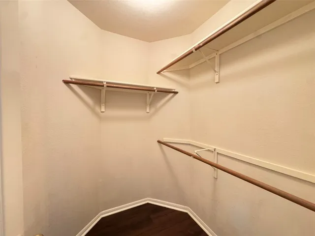 an empty room with wooden floor chandelier fan and windows